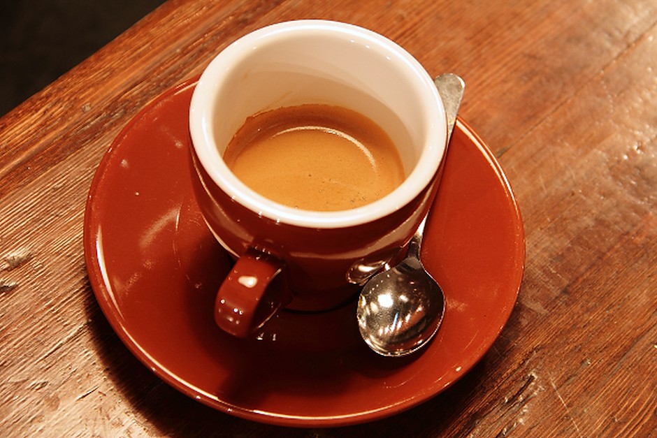 A cup of coffee on a saucer at a wooden table
