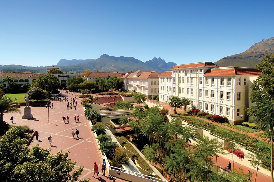 A broad green campus and mountain landscape in clear daylight